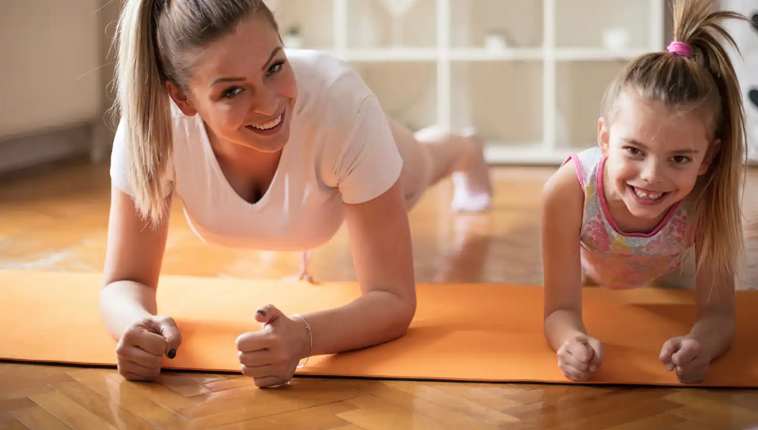 Mom and young daughter working out together doing planks to strengthen the core muscles