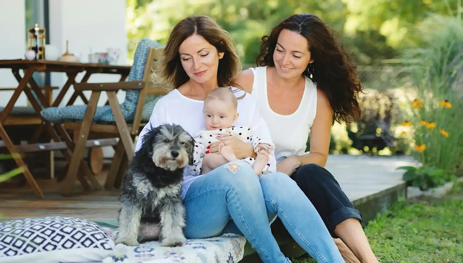 Grandmother with daughter and granddaughter happy sitting with dog. Showing confidence in multiple generations.