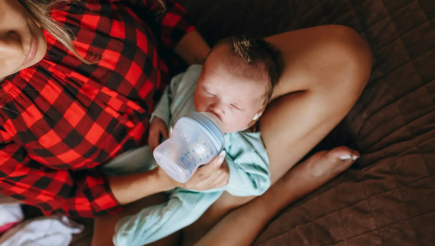 woman feeding a baby from a bottle potential breast reduction patient