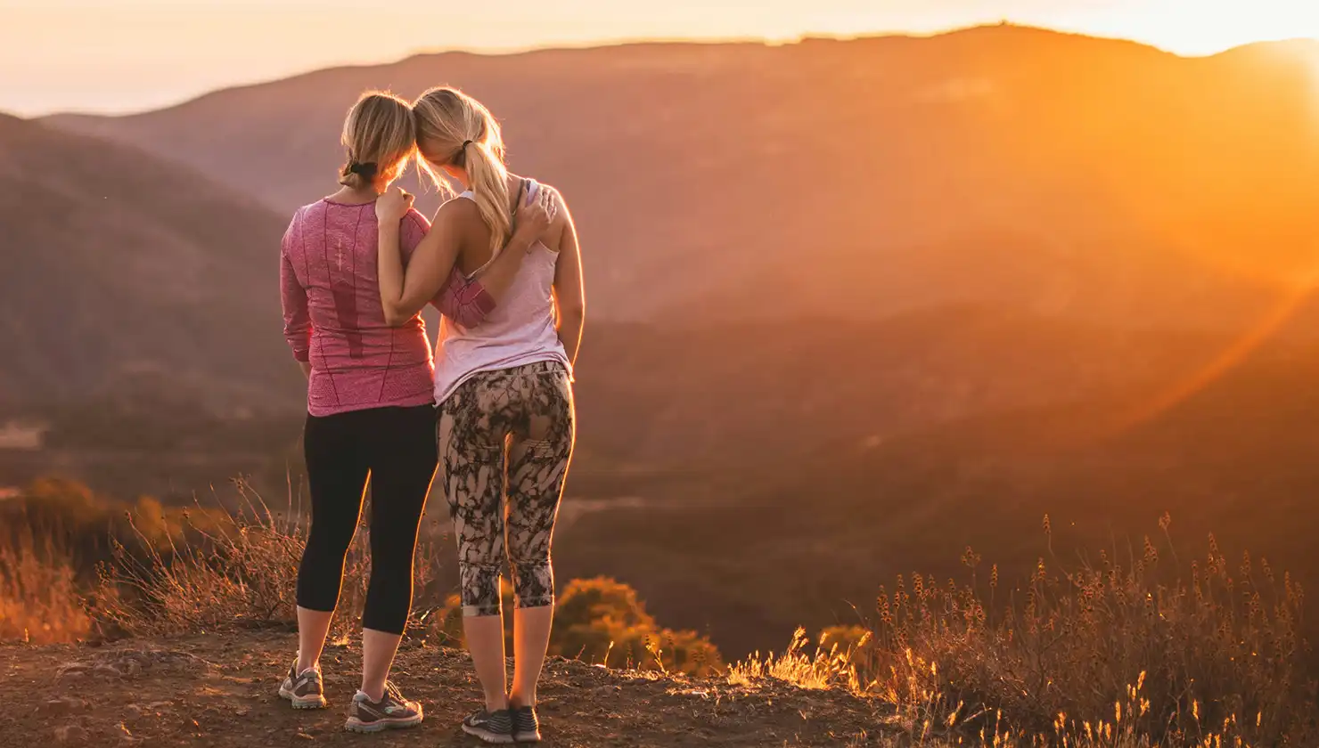 mother and daughter after hiking looking out at a sunset supporting one another emotionally