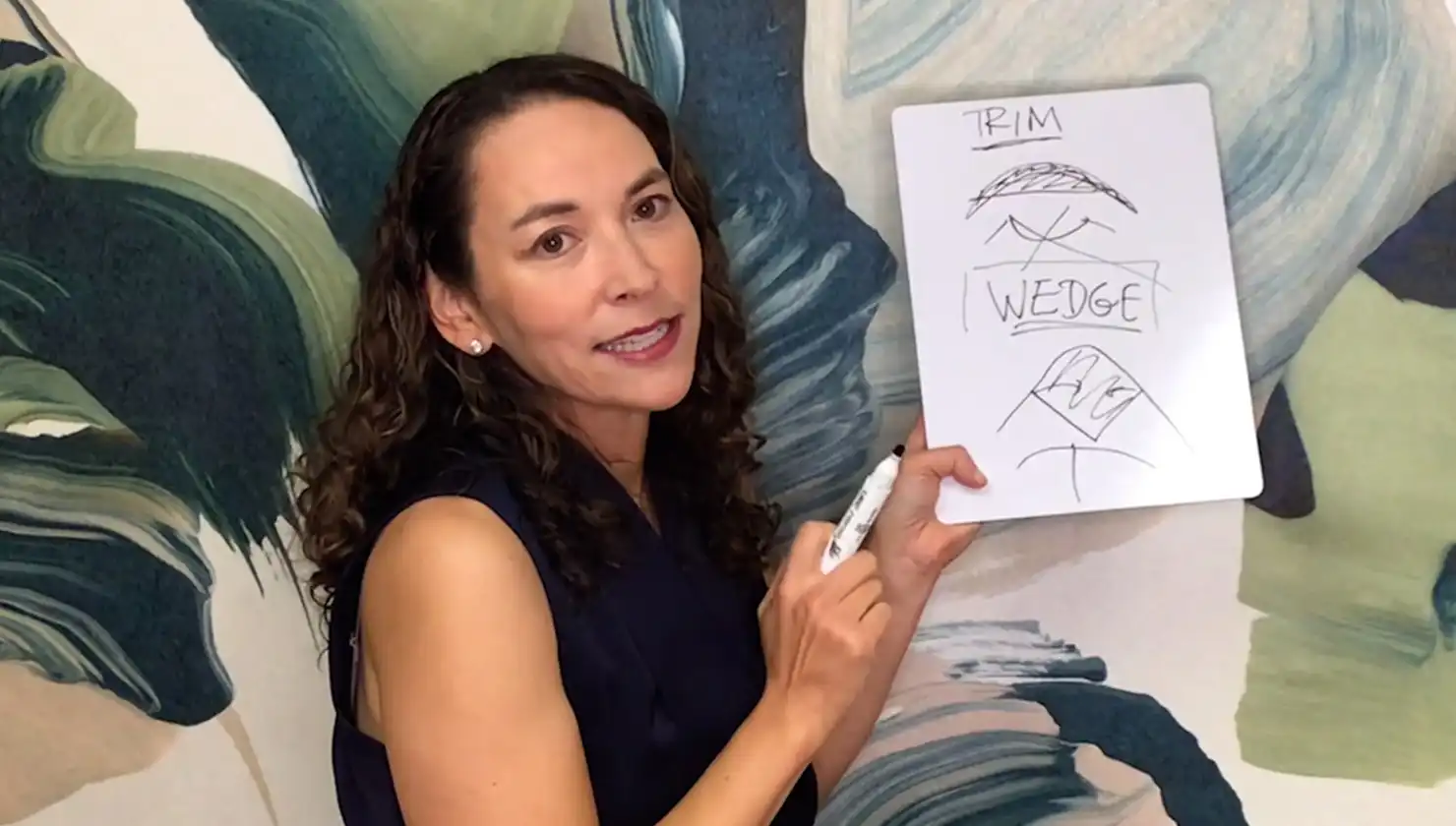 Dr. Joyce Aycock diagramming what each labiaplasty procedure does explaining a wedge vs trim using a white board